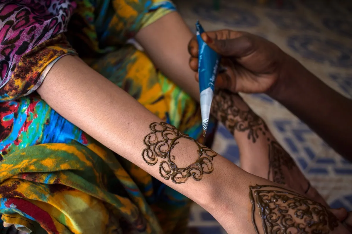 Division Multiplied, photo 10. A girl draws henna designs.